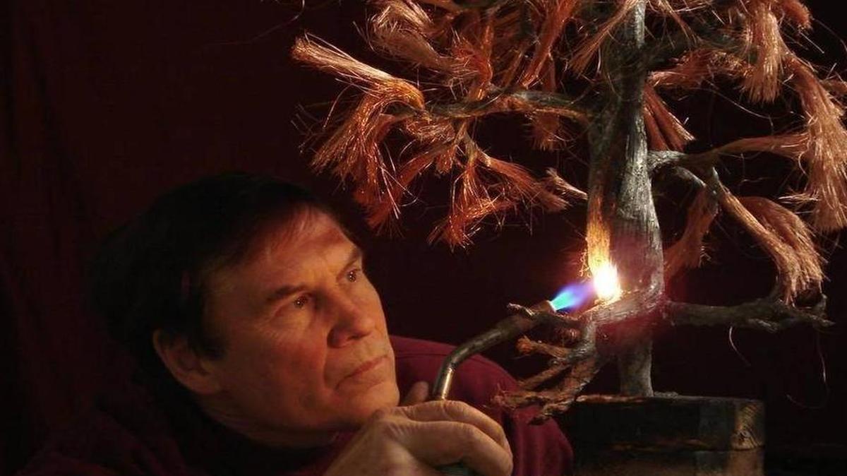 
Artist Wayne Tricklein with one of his tree sculptures.
