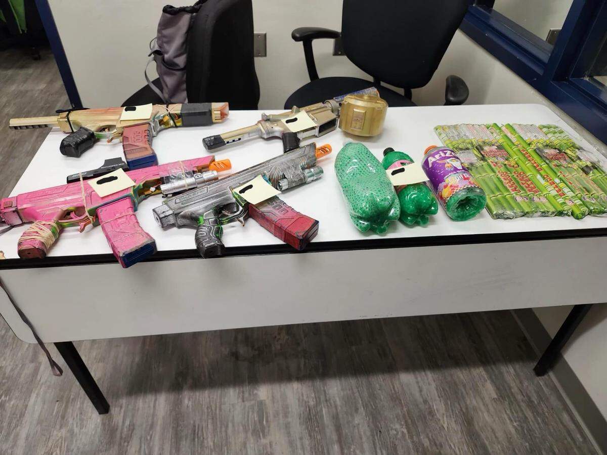 A police evidence table shows four gel blasters, bottles of soda containing water beads and roman candles.