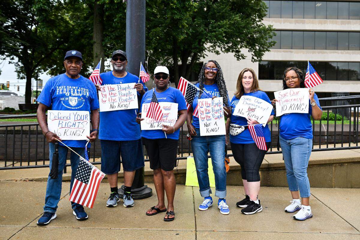East St. Louis Federation of Teachers Local 1220 union members who attended Belleville’s “No Kings” demonstration pose for a photograph holding their protest signs and American flags.