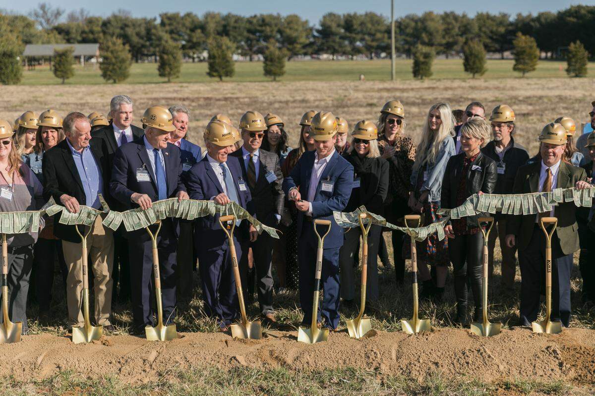 Elliot Glik cuts a ribbon made of 122 dollar bills, representing the number of years Glik’s has been in business, at a groundbreaking Wednesday for a new corporate headquarters in Collinsville.
