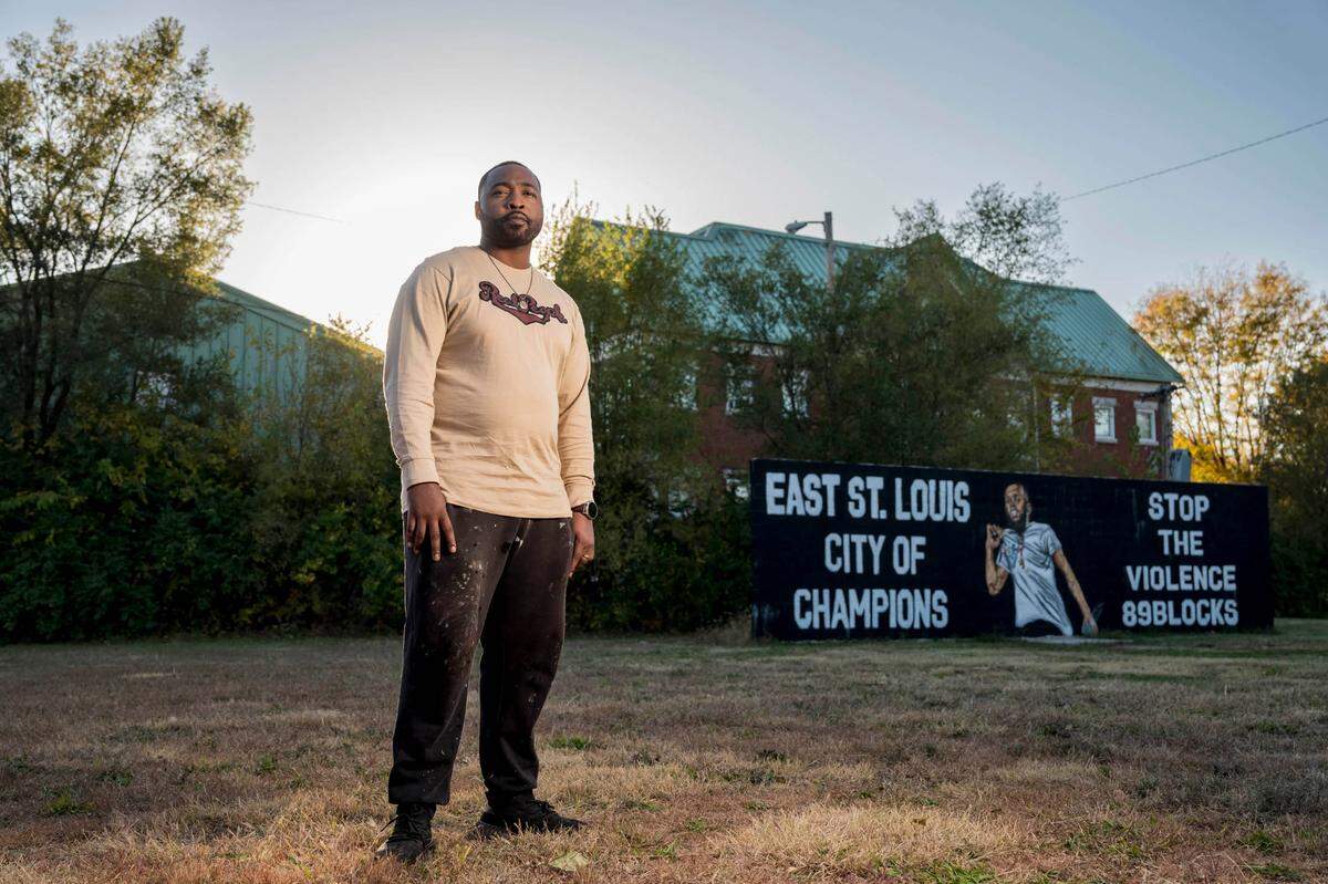 Mykael Ash stands near a mural he painted in honor of East St. Louis rapper Cedric Gooden, who died after being shot in 2019. (Whitney Curtis for KHN)