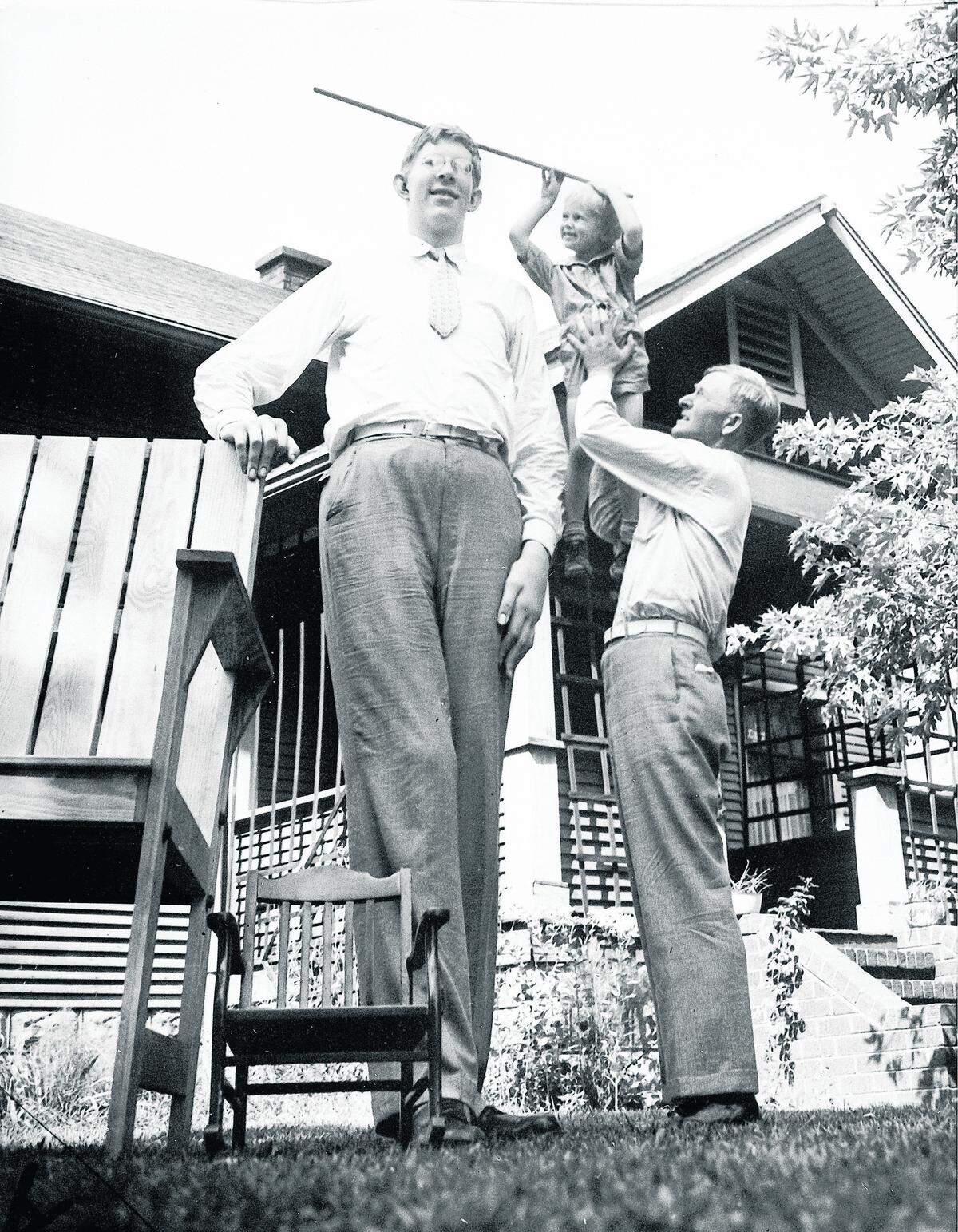 Harold Wadlow, right, lifts his 4-year-old son, Harold Jr., who rests a yard stick on his 18-year-old brother Robert's head at their home in Alton, on July 27, 1937. Robert Wadlow had an overactive pituitary gland that caused his radical growth. The large chair at left was custom built for Robert.