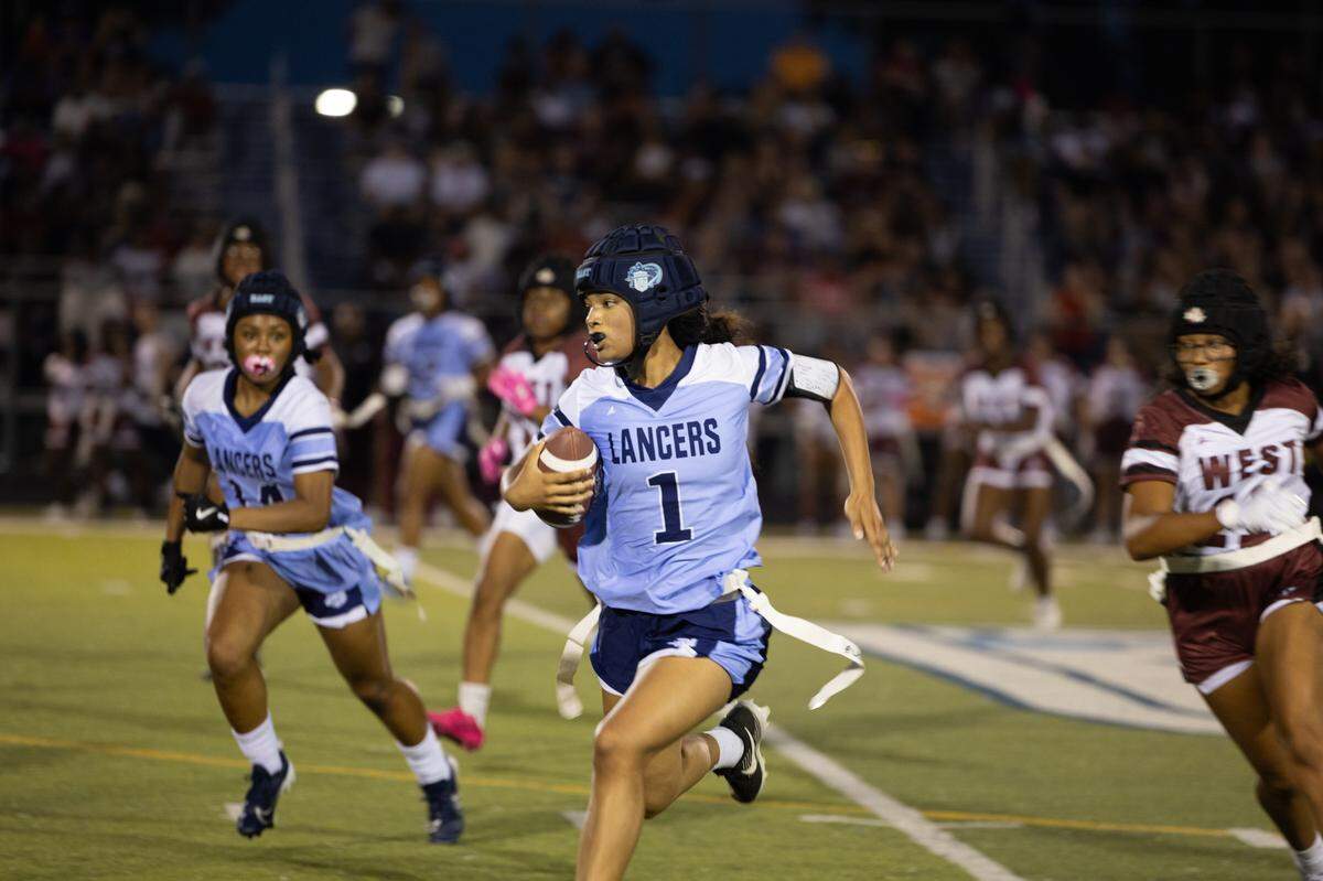 Belleville East quarterback Annyca Wilson runs past the Maroons’ defense during the inaugural girls flag football game at Charles Woodford Field on Aug. 28, 2024.