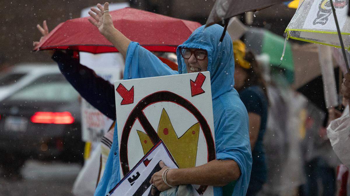 Protesters wave to passers-by during a deluge at the No Kings protest on the Belleville Public Square in October. Here’s when the next No Kings protests will be held locally.