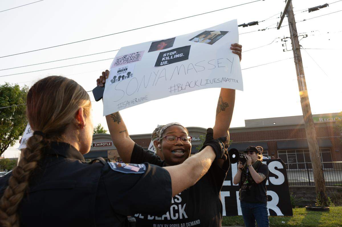 A demonstrator holds a sign in front of a police officer after being instructed to move from Lincoln Highway during a protest in Fairview Heights on July 24, 2024 against the police killing of Sonya Massey in her Springfield, Ill. home.