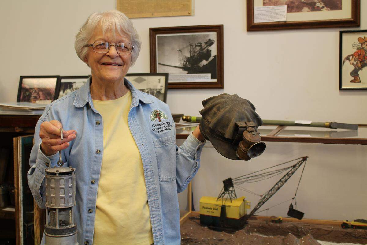 Kay Jetton, president of Marissa Historical and Genealogical Society, shows off an antique coal-miner’s cap and a methane-detecting safety lamp in the “Coal Country” exhibit at Marissa Museum.