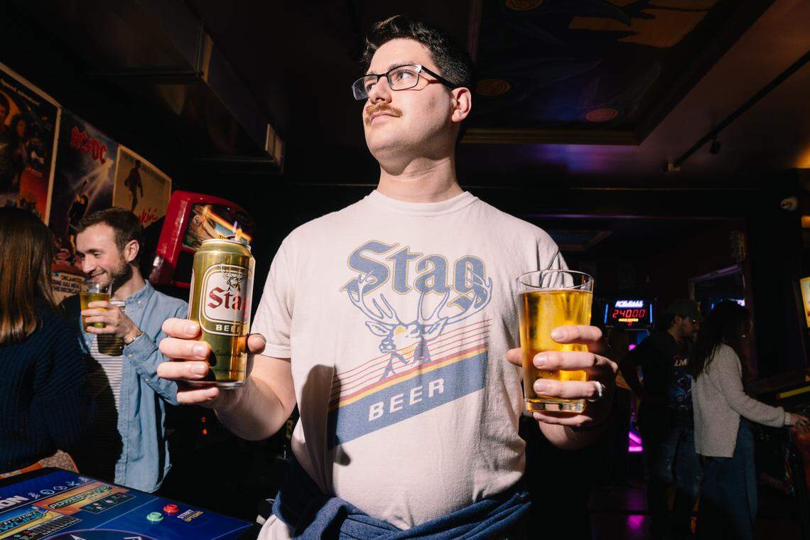 Steven McCoy, of Florissant, double-fists a can and glass of Stag Beer during a wake for the beer being sold in kegs at The Crow’s Nest on Friday, Feb. 27, 2026, in Maplewood.