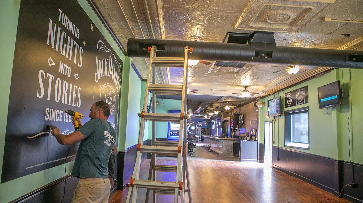 Joe English, of Sikorski Signs, installs a wall graphic at Big Daddy’s 618 restaurant and bar in downtown Belleville last spring. At that time, Illinois was under its first coronavirus-related indoor-dining ban.