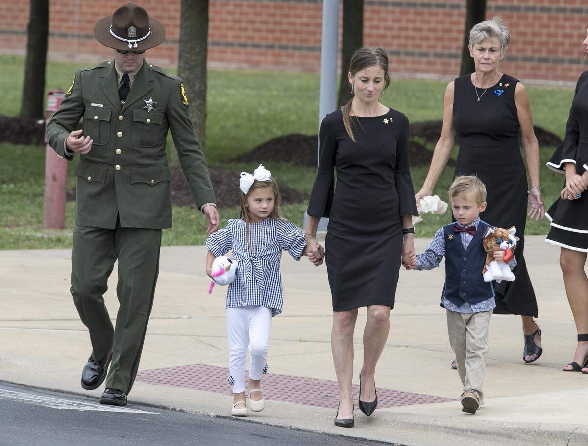 Whitney Hopkins, the wife of Illinois State Police Trooper Nick Hopkins, leave’s the funeral service at Waterloo High School with their 4-year-old twins.