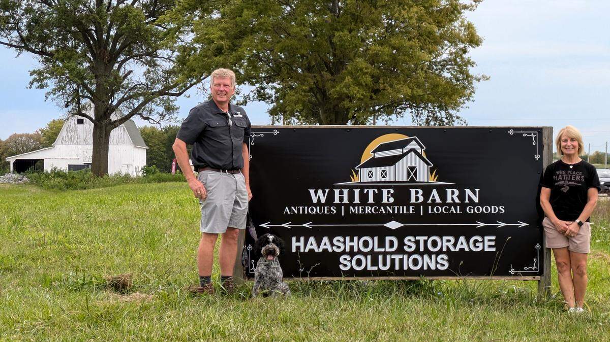 White Barn Antiques and Mercantile and HaasHold Storage Solutions owners Dennis and Kim Haas and their dog, Romeo. The white barn is visible in the background.