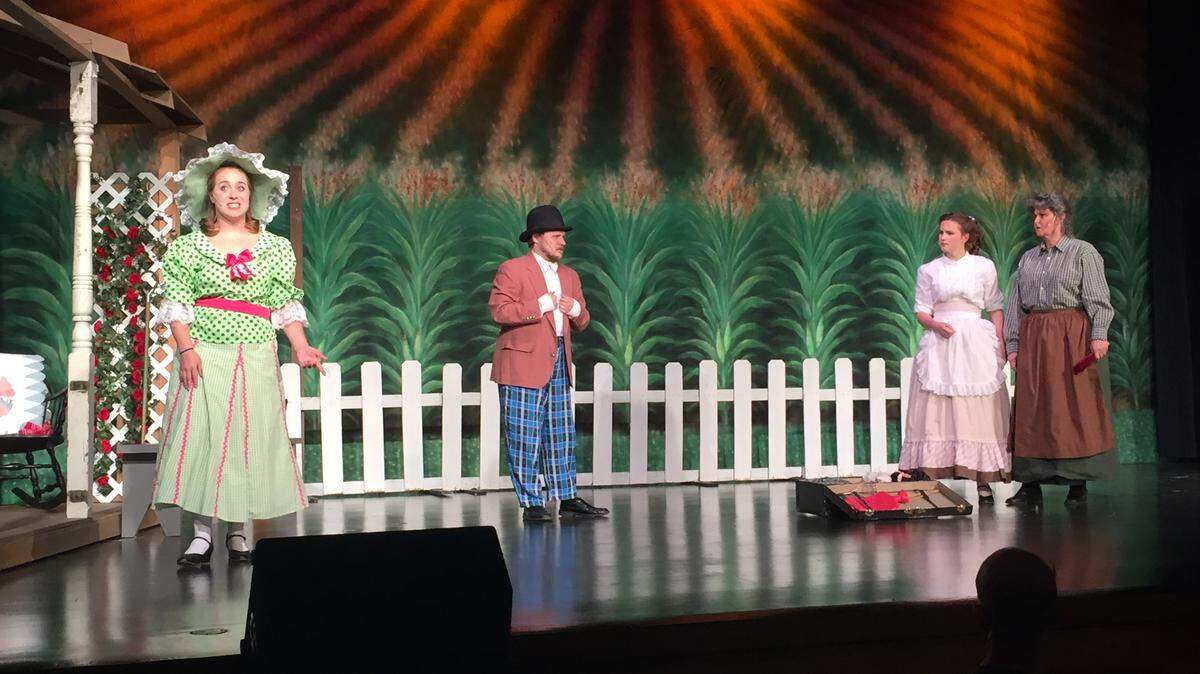 Ado Annie (Hannah Wudtke) looks on in surprise as Ali Hackim (Tim Albaugh) attempts to sell Laurey (Olivia Bosaw) and Aunt Eller (Lynne Huelsmann) some wares in a scene from Oklahoma!