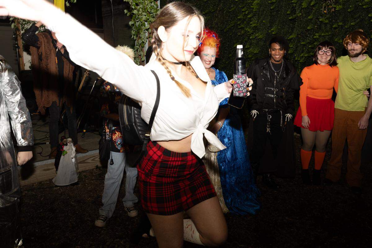 Participants in a costume party smile on as a contestant dressed as Britney Spears shows off her costume.