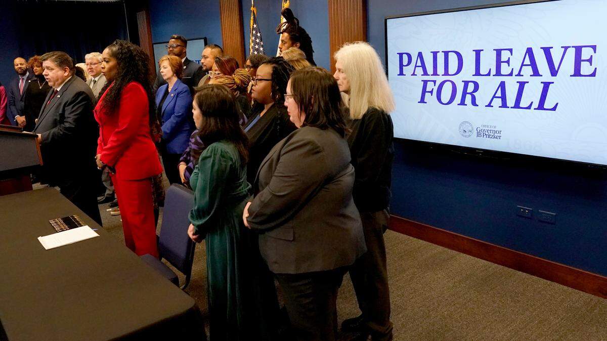 Illinois Gov. J.B. Pritzker, right, talks about the merits of the Paid Leave For All Workers Act before signing it into law on Monday, March 13, 2023, in Chicago. Illinois became one of three U.S. states to require employers to offer paid time off for any reason starting in January of 2024. (AP Photo/Charles Rex Arbogast)
