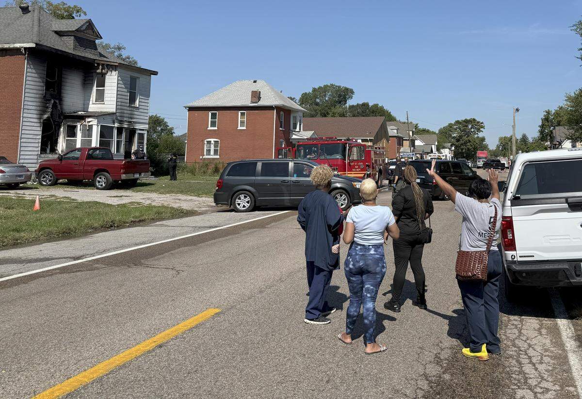 Neighbors and family members pray as the bodies of three people are transported away from a house at 3316 Bond Ave. in East St. Louis following a fatal fire there Friday morning.