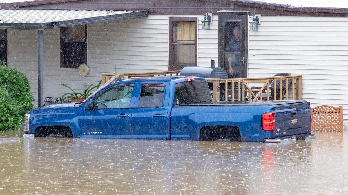 A resident of a mobile home park, located near the intersection of Illinois 159 and 161 in Swansea, looks out their front door to a flooded Wolf Branch creek Tuesday.