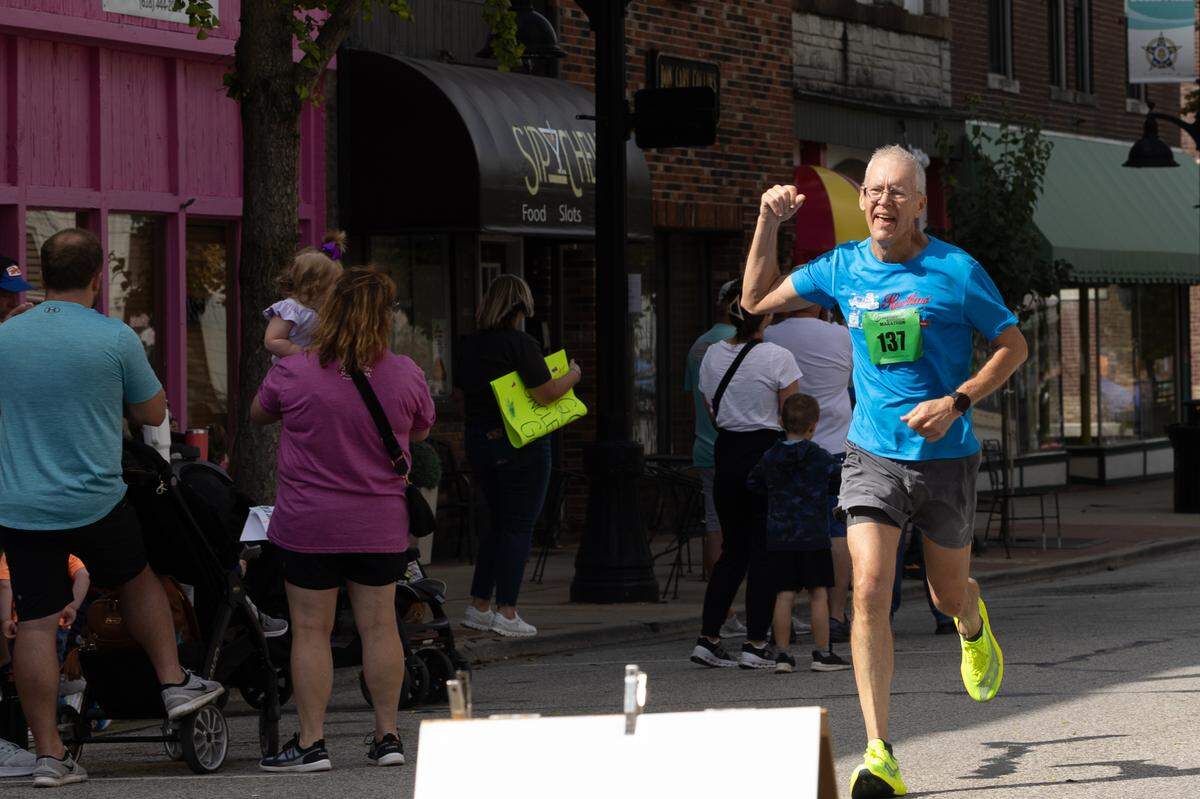 Glen Schepers, 62, of Celestine, Indiana raises his fist as he crosses the finish line at the Belleville Marathon on Sept. 28, 2024. Schepers didn’t run a marathon until he was in his 50s, and credits his son as his motivation. “The first thing that goes through my head when I do these is, ‘why?’” Schepers said. “But then the blood gets pumping and it’s such a rush.”