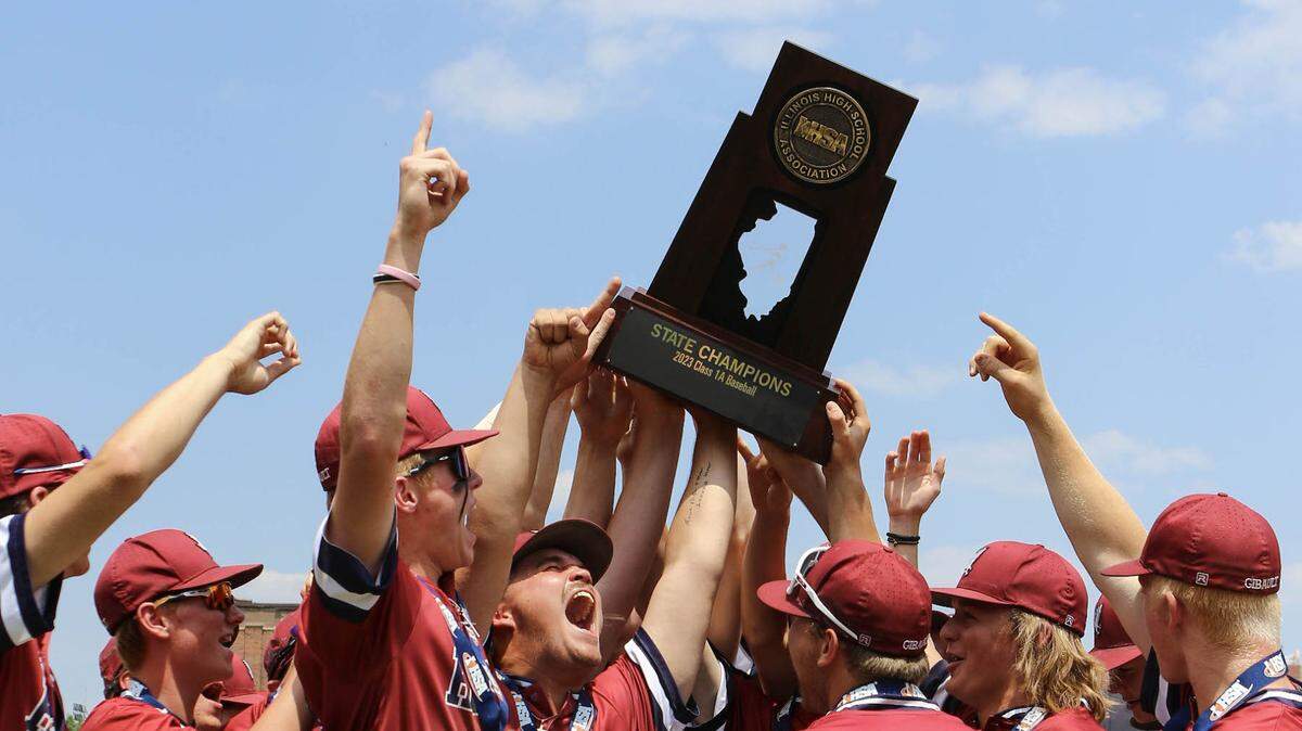 Gibault players celebrate with the championship trophy after defeating Henry H-Senachwine 8-0 in Saturday’s IHSA Class 1A state championship game at Dozer Park in Peoria. The win secured the second state championship in the baseball program’s history.
