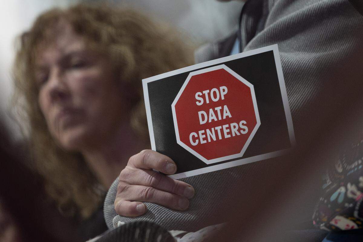 A Troy resident holds a sign that reads “Stop data centers” at a meeting with city and development representatives about a possible data center in the city.