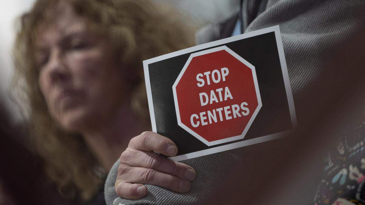 A Troy resident holds a sign that reads “Stop data centers” at a meeting with city and development representatives about a possible data center in the city.