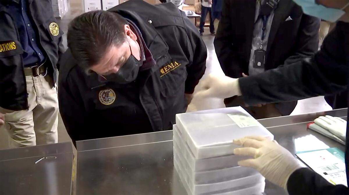 Illinois Governor J.B. Pritzker examines the first shipment of a coronavirus vaccine on Monday to the Illinois Strategic National Stockpile. Supplies are being distributed across the state for administration to health-care workers this week.