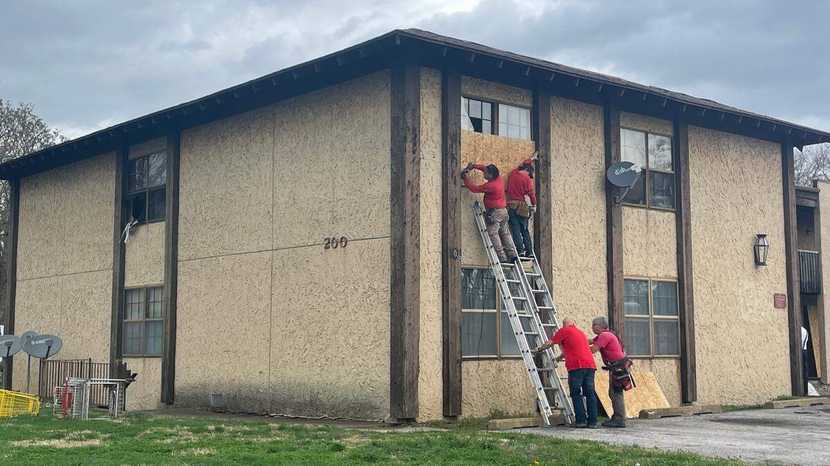 Workers install plywood over broken windows at an apartment building at 200 N. 45th St. in Belleville after a fire Wednesday.