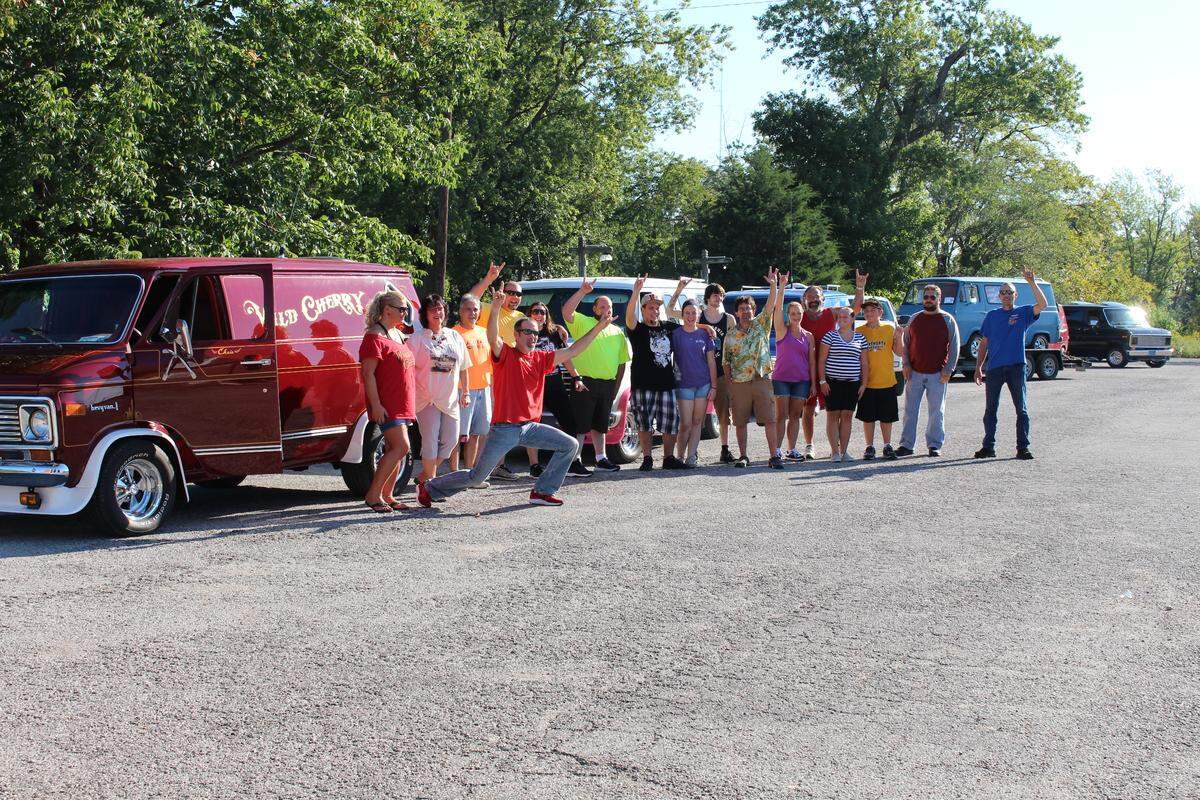 Chris Carter, who restored the Wild Cherry van, hams it up (in red shirt) on Sept. 15 for photographers at the kick-off of a caravan trip from Maryville to Los Angeles.