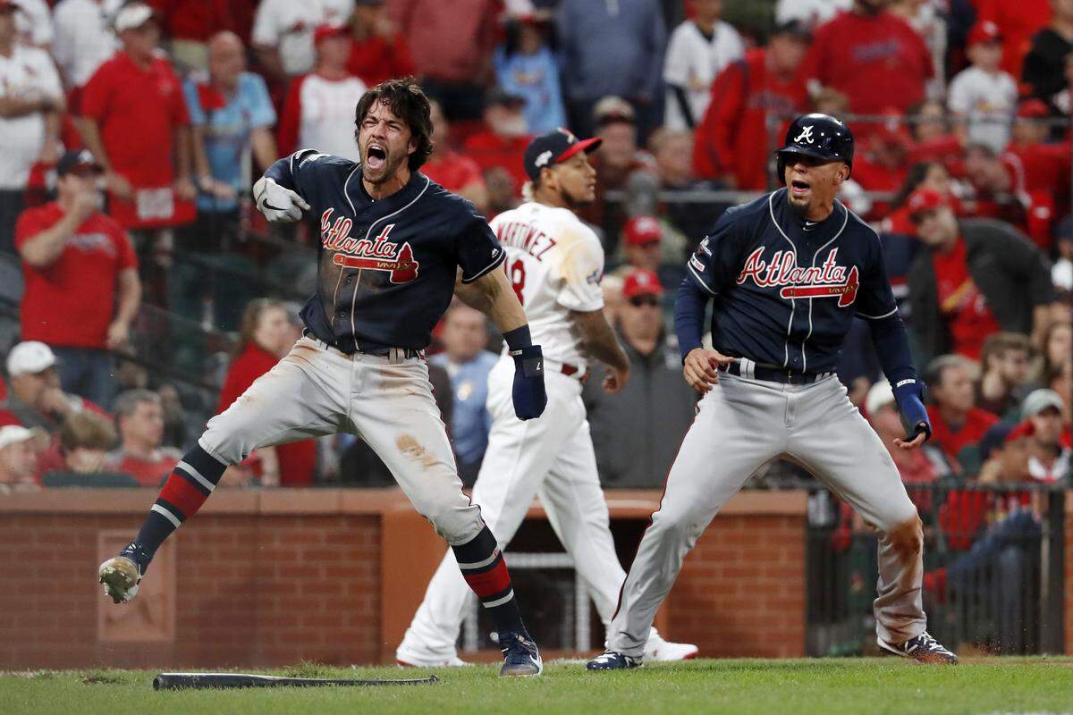 Atlanta Braves’ Dansby Swanson, left, and Rafael Ortega, right, celebrate after scoring as St. Louis Cardinals relief pitcher Carlos Martinez (18) walks in the background during the ninth inning in Game 3 of a baseball National League Division Series on Sunday, Oct. 6, 2019, in St. Louis. (AP Photo/Jeff Roberson)