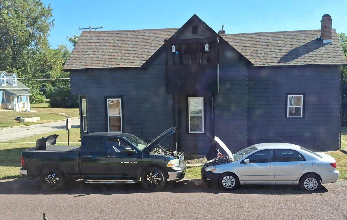 George Green, under hood at right, works on vehicles on Bunsen Avenue, near its intersection with South 19th Street in Belleville. Neighbors have accused him of improperly operating a business in a residential area. He maintains that he’s only doing repair work for family members.