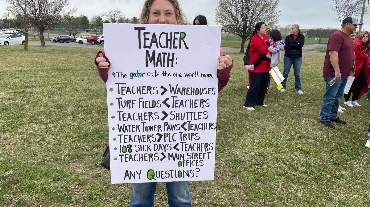 Rachel Case, co-president of the Columbus Elementary PTO in Edwardsville, holds up a sign in support of teachers ahead of Monday night’s school board meeting at Liberty Middle School. The board voted 4-3 to cut 16 non-tenured teachers for the next school year.