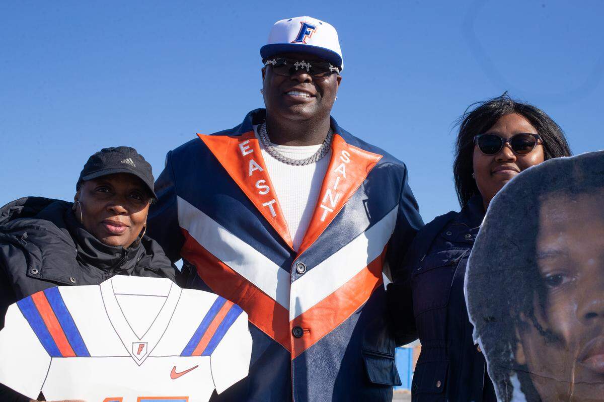 Tracy Douglas, Artagus Williams and Ranada Turner wait along the parade route to show support to inside linebacker Keylan Lagrant. Williams, center, has been deemed the Flyers “No. 1 fan” by some members of the community. He has attended every game of the season.
