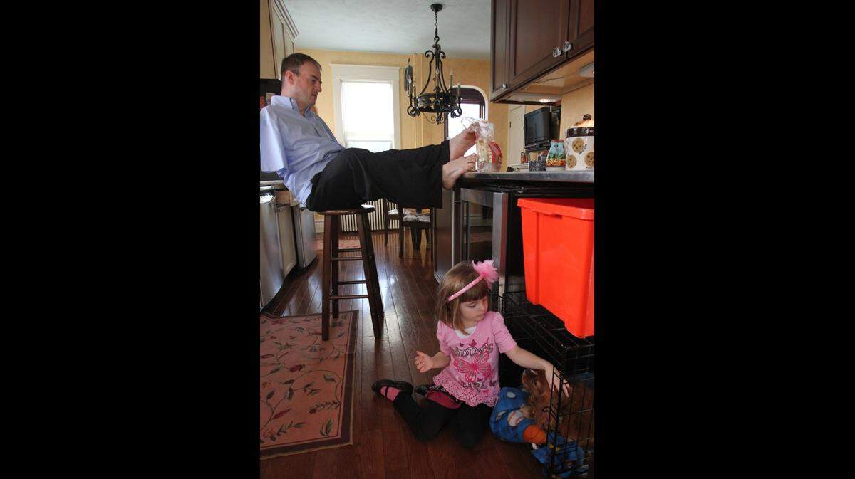 John Foppe works in the kitchen while his 4-year-old daughter, Faith, plays in the floor.