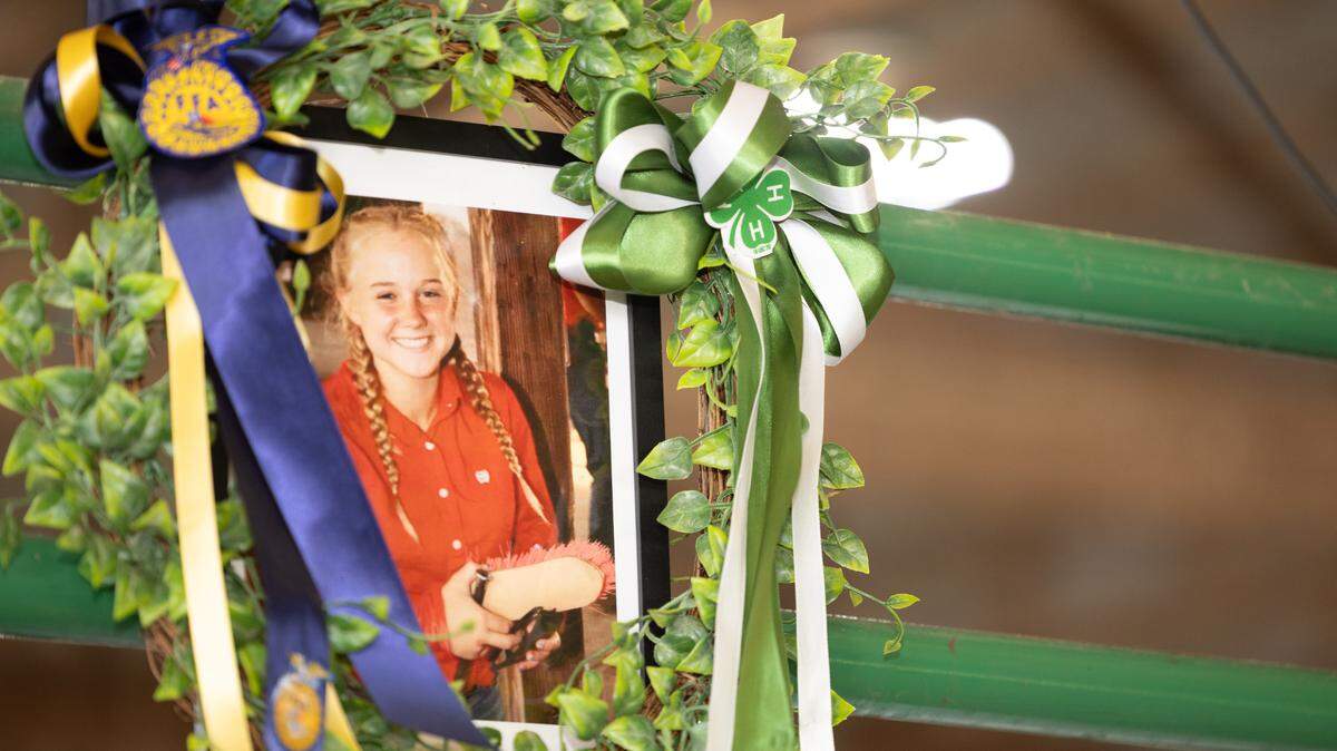 A portrait of Emma Schultheis hangs above the FFA and 4H livestock auction block in July at the Monroe County Fair in Waterloo. 