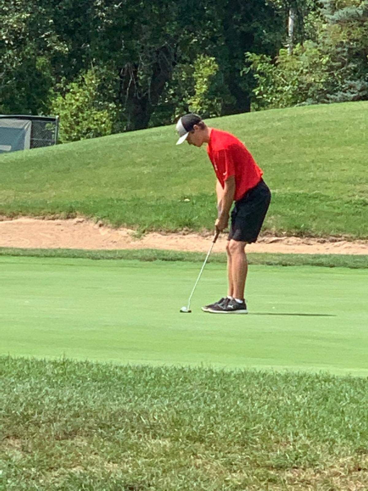 Highland senior Mason Emig setts up a put during the Madison County Tournament at Belk Park Golf Course in Wood River on Aug. 18. Highland placed third in the large school division with a 323 score.