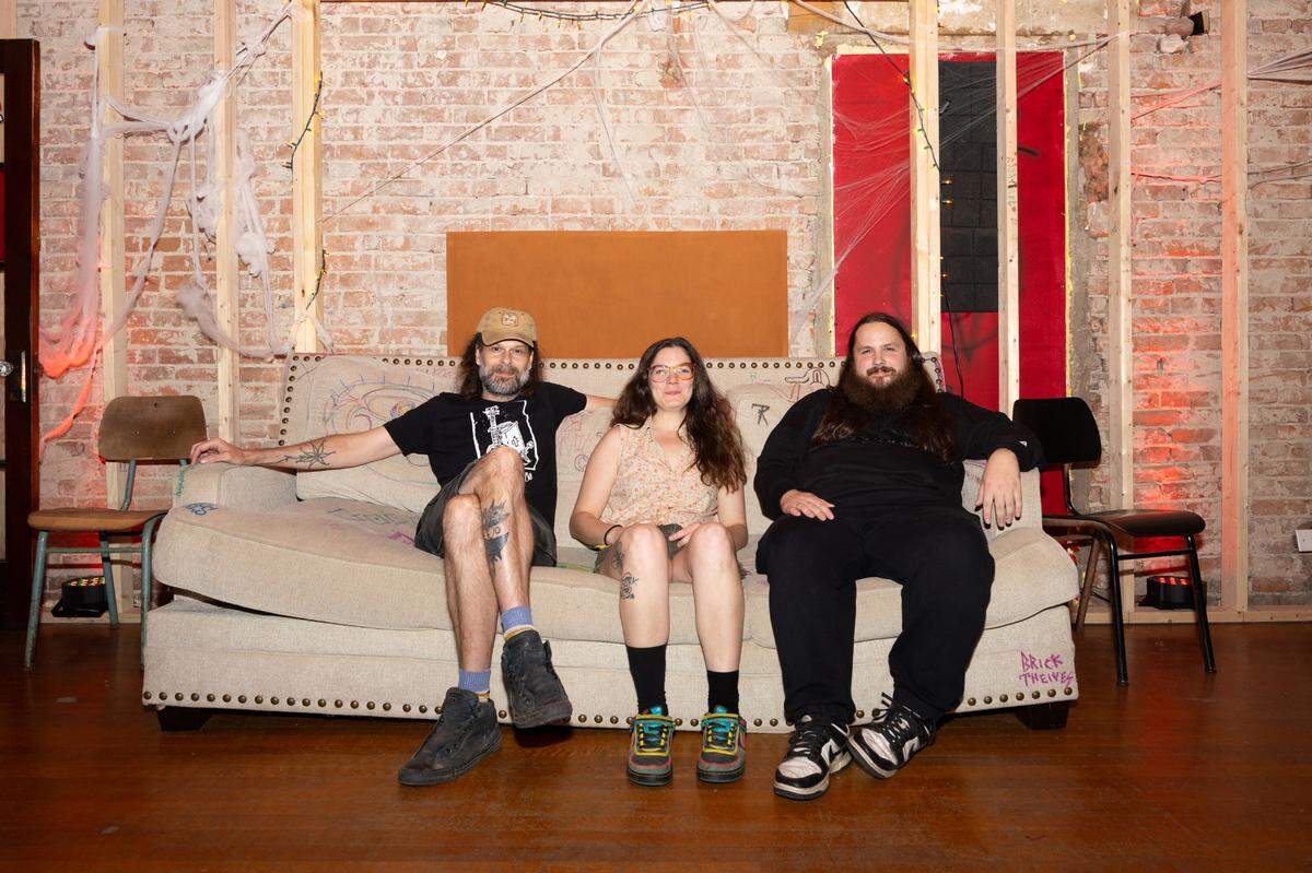(L-R) Gabe Kimme, Jackie Eberle and Richard Summitt sit on a couch in an indoor performing space built into their Belleville, Ill. home on Oct. 3, 2024.