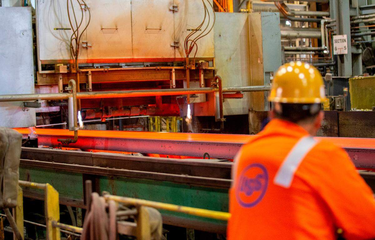 A U. S. Steel worker watches as a slab of steel moves through the production process.