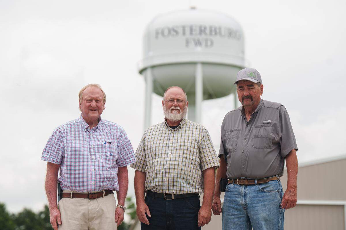 Greg Bates, Mark Voudmard, and Steve Strohbeck, left to right, stand together for a portrait in front of the Fosterburg water tower on Thursday, July 17, 2025 in Fosterburg, Illinois.