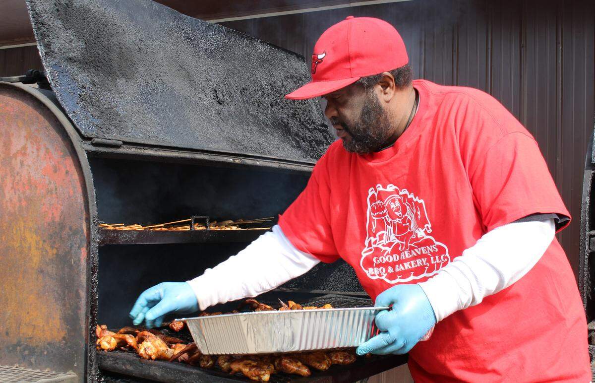 Charles Williams takes chicken wings out of a smoker at Good Heavens BBQ & Bakery in East St. Louis, which will give children a hot dog and bag of chips Thursdays through Saturdays while schools are closed.