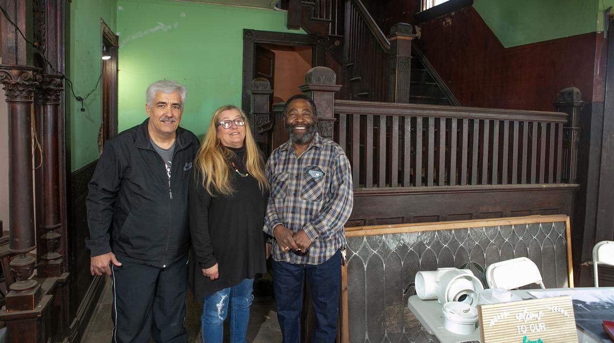 Eric Gentz, left, and his sister, Vickie Gentz, grew up in “The Pink House” in Aviston. They’re shown in the foyer with Vickie’s fiance, Tommy Williams. The home is now under renovation by new owners.