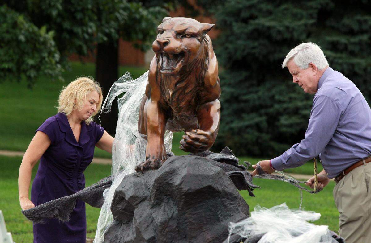 McKendree University Vice President of Student Affairs Joni Bastian and President James Dennis remove the protective wrapping on a 2,500-pound bearcat statue in 2014.