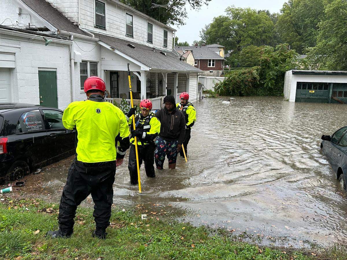 A resident is escorted out of their home through flood water by Belleville firefighters on July 16, 2024.