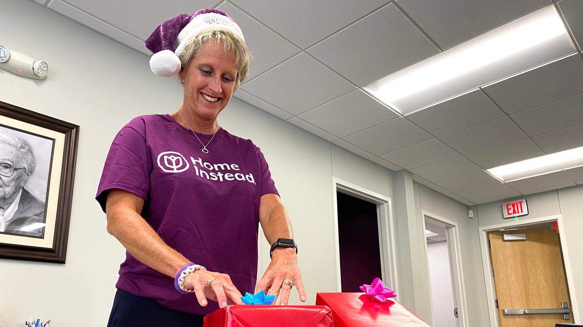 A Home Instead volunteer wraps gifts