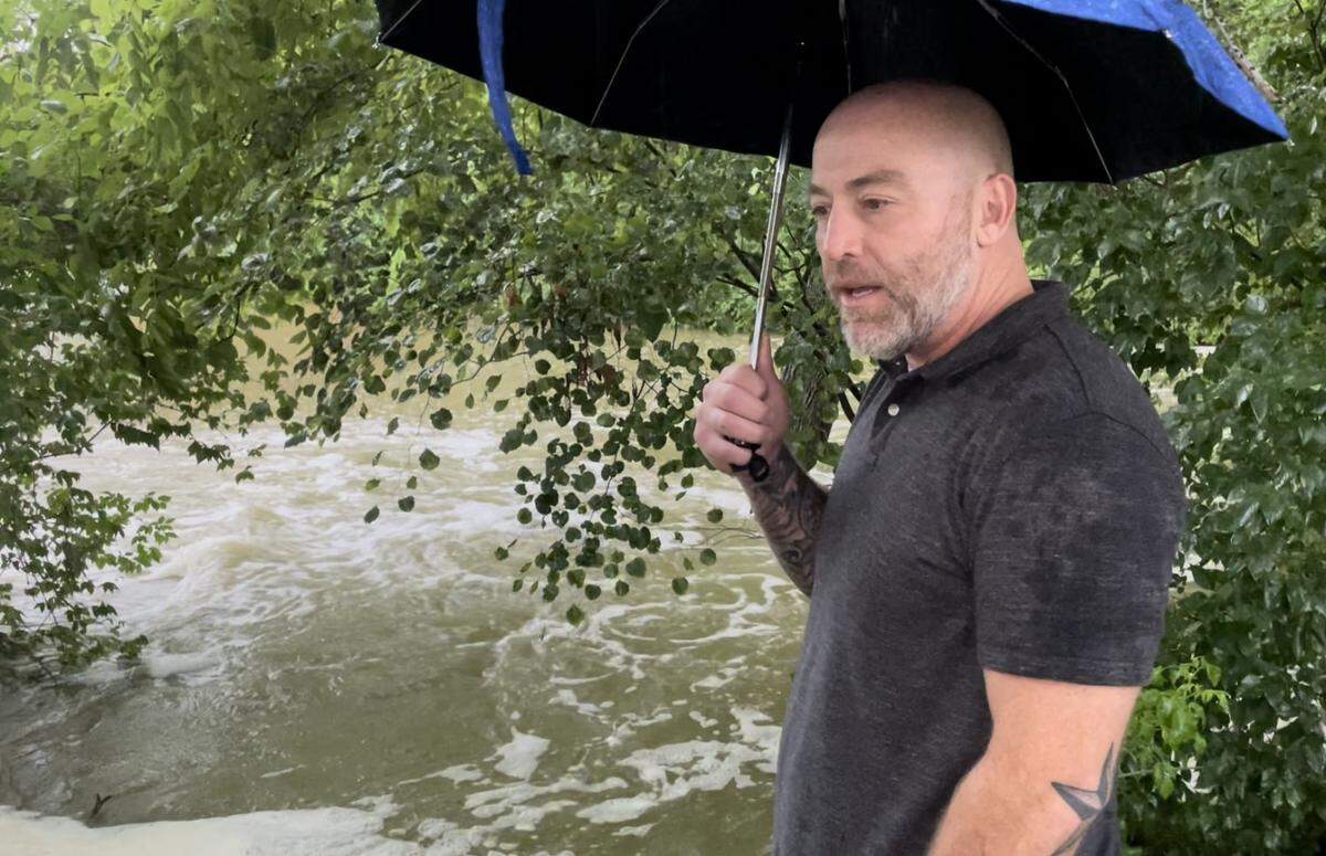 Vincent Mudd, surveys the rising creek flowing through his back yard on Lake Lorraine Drive in Swansea.