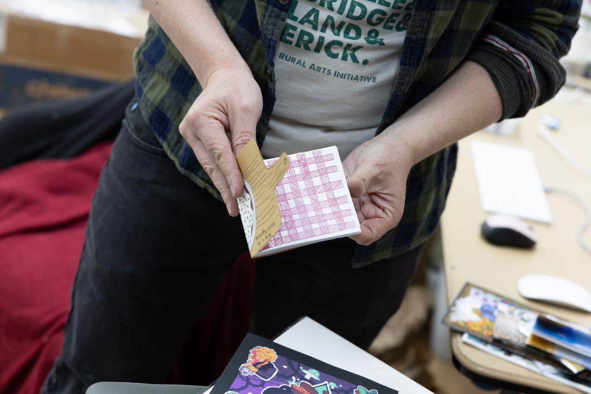 Danny Houk holds a zine by artist Tori Holder inside the future location of Public Defender Art + Zines, which is scheduled for a grand opening May 15.