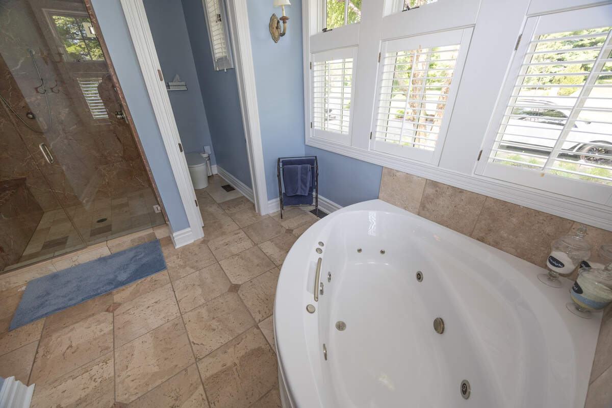 The bathroom attached to the master bedroom comes with a jacuzzi tub, two-person shower and two sinks with ornate hardware.
