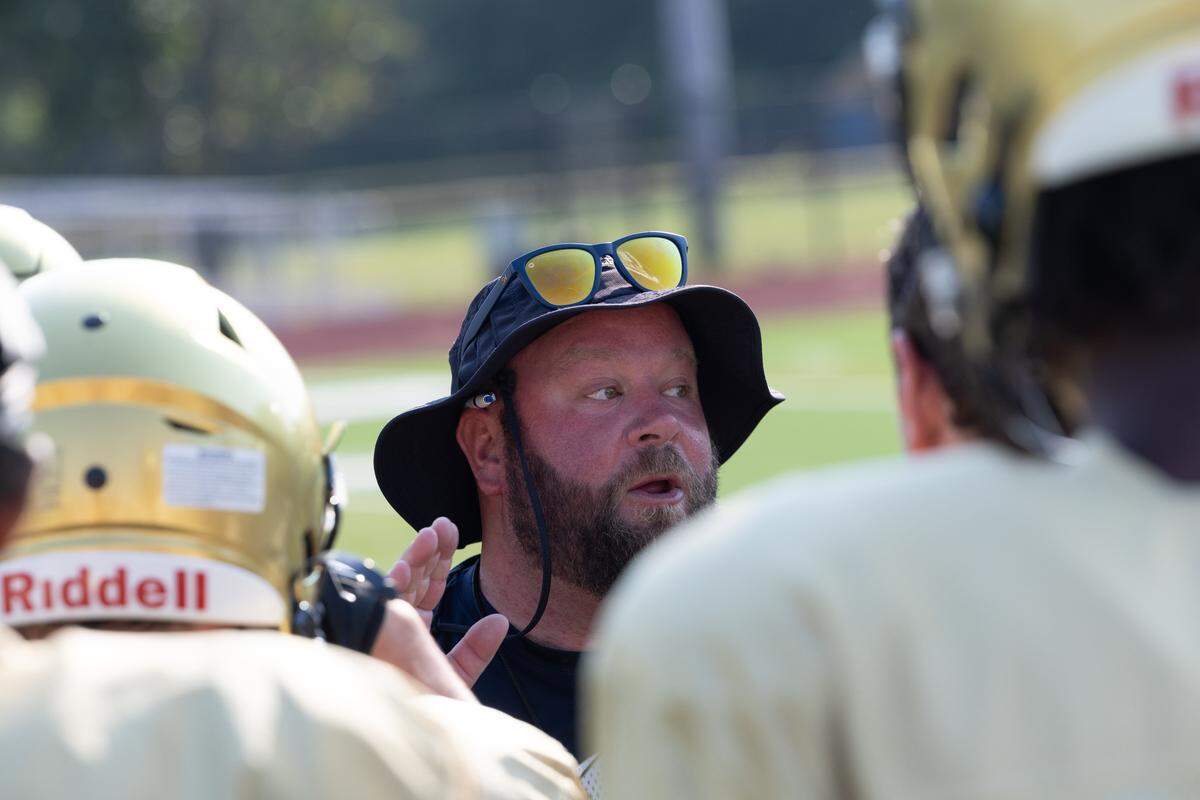 Althoff head football coach Austin Frazier speaks to the Crusaders prior to a scorching 95-degree practice on Saturday.