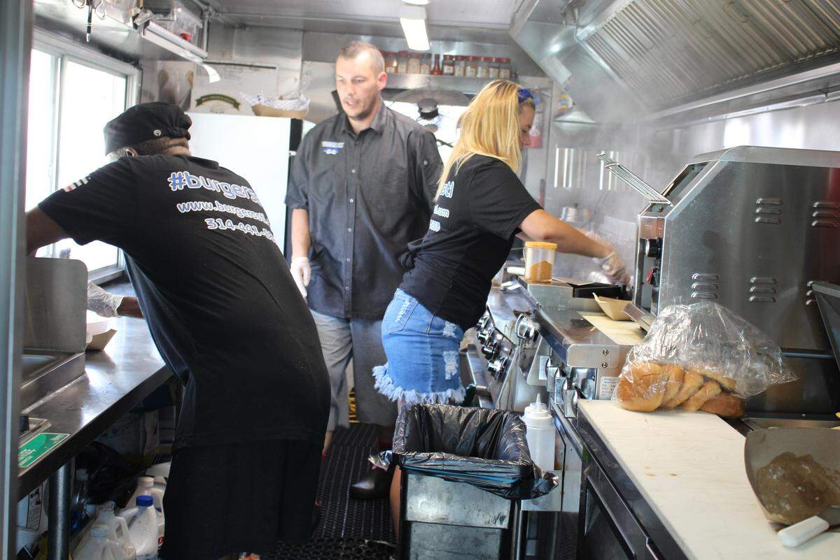 Matt Foley, center, owner of the Burgers STL food truck, works in the steamy kitchen with employees George “Geo” Singleton, left, and Chloe Brown.