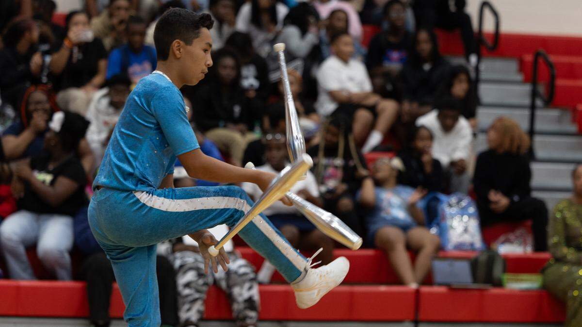 A young gymnast representing Mexico in the UniverSoul Circus troupe juggles chrome bowling pins on Aug. 14, 2024 at Mason-Clark Middle School.