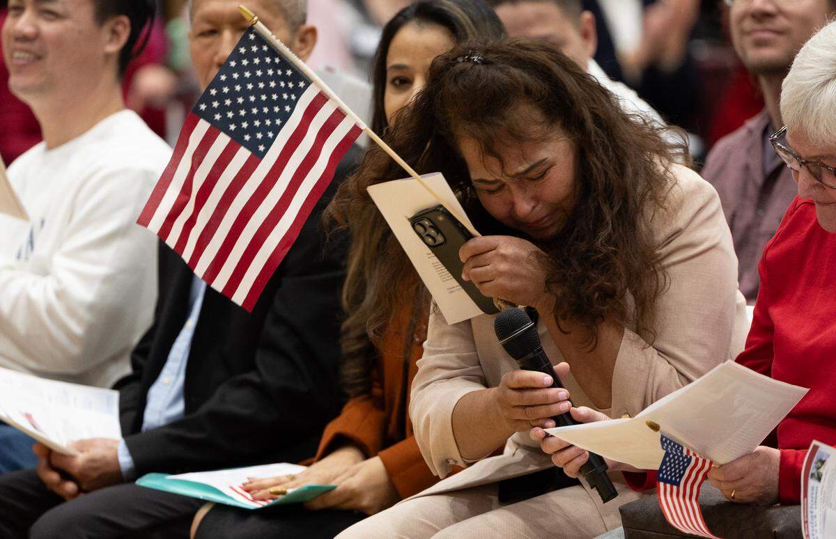 A woman who immigrated from Mexico is overcome with emotion after becoming a U.S. citizen on Friday at Belleville West High School.