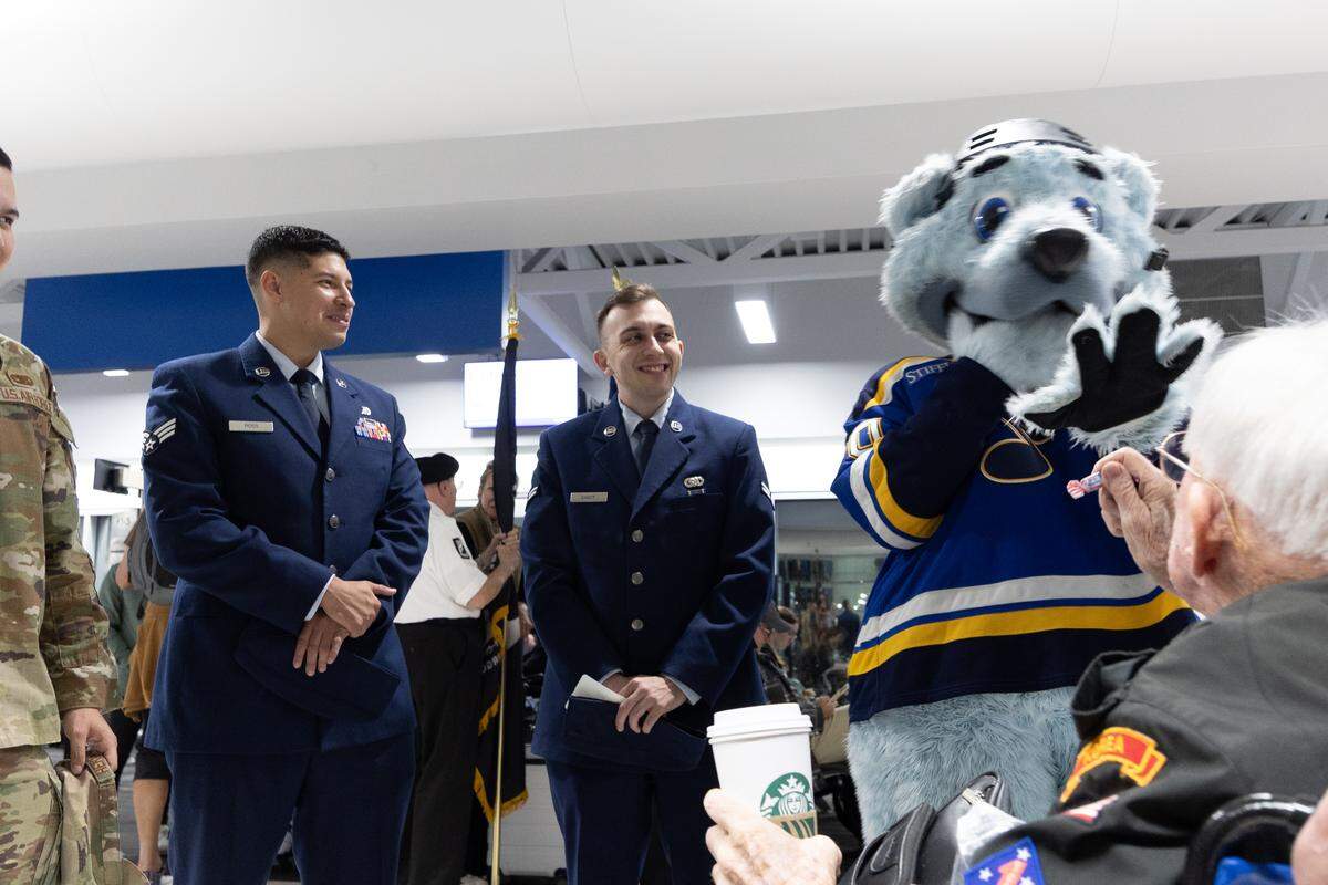 Greater St. Louis Honor Flight founder Harry Hope jokes with St. Louis Blues mascot “Bluey” as they wait for veterans to disembark from their plane.
