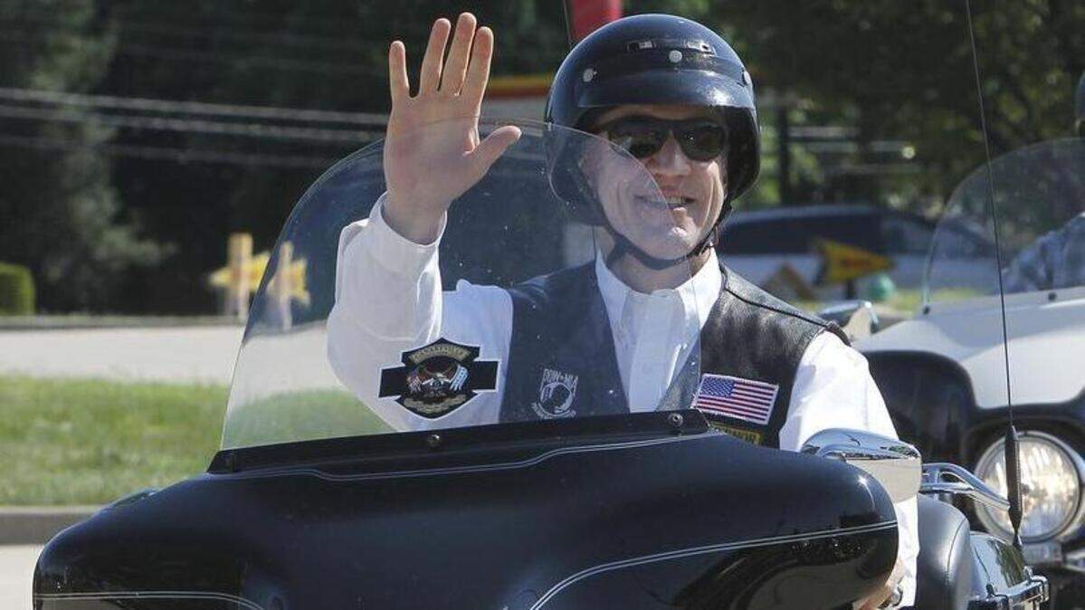 Illinois Gov. Bruce Rauner waves July 16, 2016, as he rides his Harley-Davidson motorycle into the Frieze Harley-Davidson dealership in O'Fallon. Rauner is an avid motorcyclist, and said he's been riding since he was 15 years old. He also competed in motocross racing with his brother.
